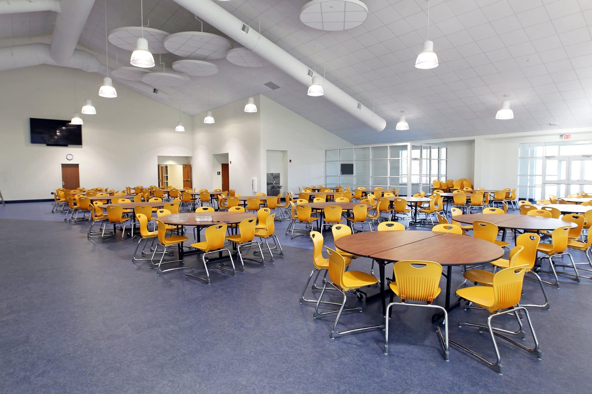 On y voit un intérieur d'établissement scolaire design 4 chaises jaune en bois
