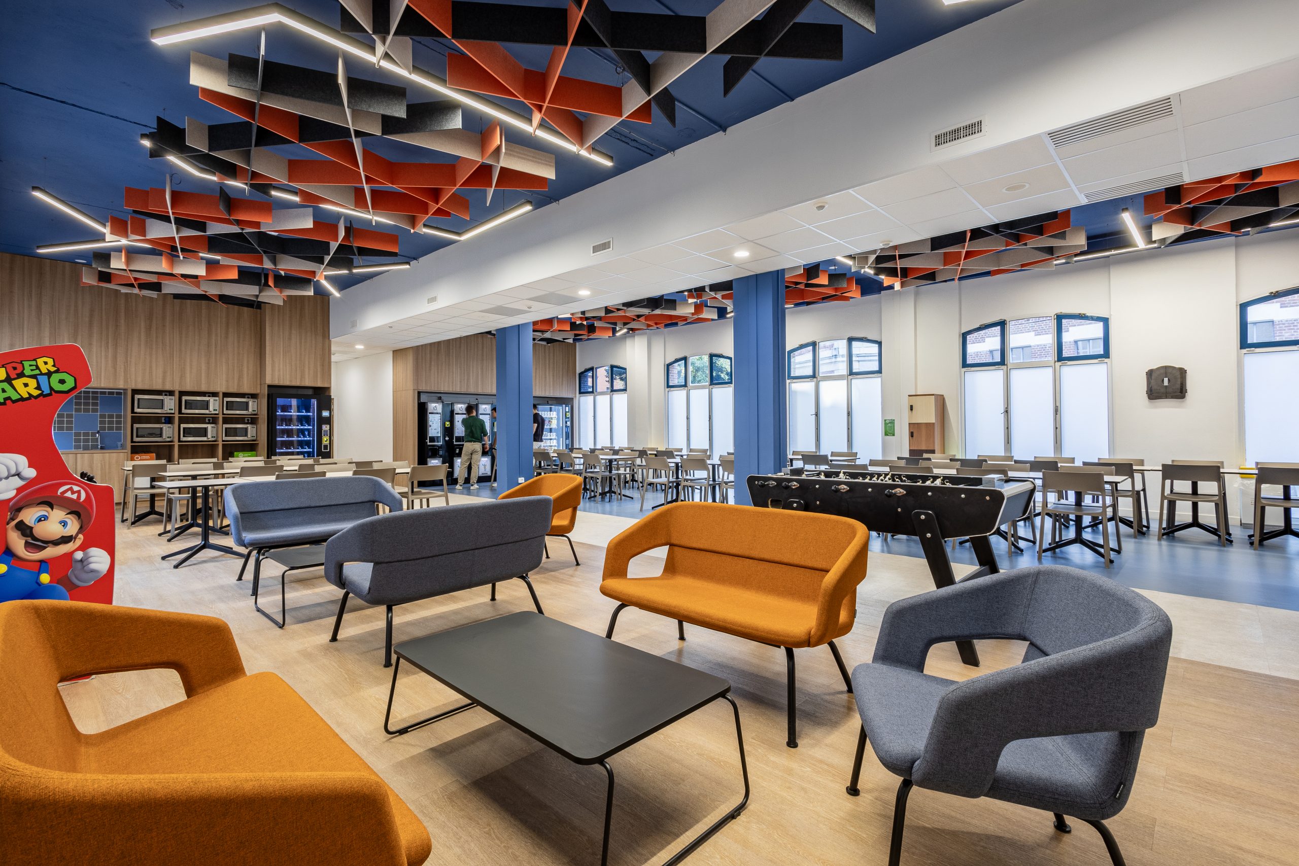 On y voit un intérieur d'établissement scolaire avec des solutions acoustiques au plafond