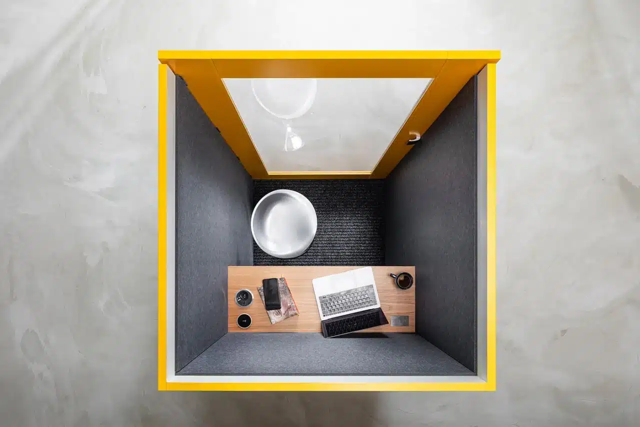 On y voit une cabine acoustique design avec une personne a l'intérieur