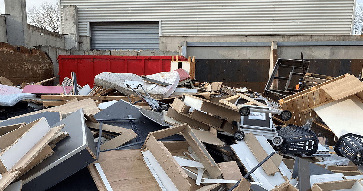On y voit un conteneur rempli de mobilier professionnel usé